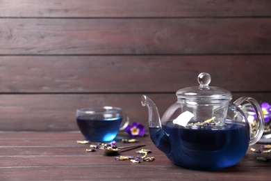 Organic blue Anchan in teapot on wooden table, space for text. Herbal tea