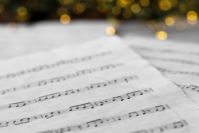 Photo of Closeup view of note sheets against blurred lights. Christmas music