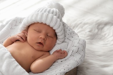 Photo of Cute newborn baby in warm hat sleeping on knitted blanket