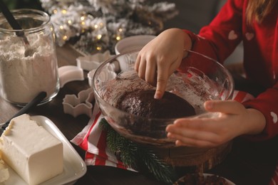Little child making Christmas cookies at wooden table, closeup
