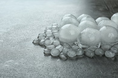 Many melting ice balls on dark grey table, space for text