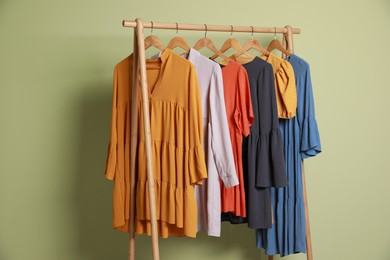 Collection of trendy women's garments on rack near green wall. Clothing rental service