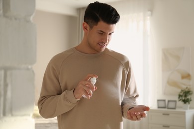 Man applying spray sanitizer onto hand at home