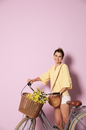 Portrait of beautiful woman with bicycle on color background