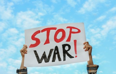 Woman holding poster with words Stop War against sky outdoors, closeup
