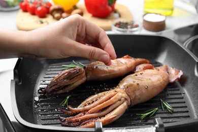 Photo of Woman cooking fresh squids on grill pan, closeup