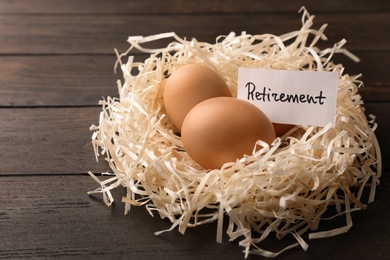 Eggs and card with word RETIREMENT in nest on wooden background. Pension concept