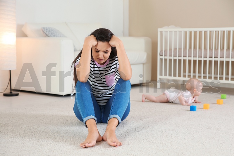 Photo of Young mother suffering from postnatal depression and little baby in room