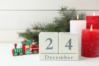 Christmas Eve - December 24. Block calendar and festive decor on white wooden table