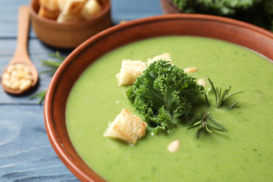 Tasty kale soup with croutons on table, closeup