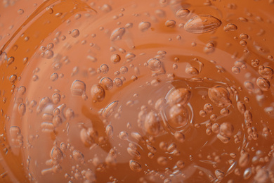 Pure transparent cosmetic gel on orange background, closeup