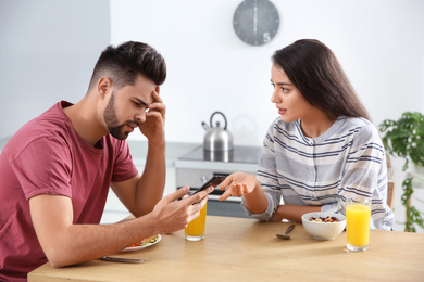 Young man with smartphone ignoring his girlfriend at home