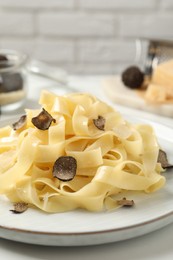 Delicious pasta with truffle slices served on white table, closeup
