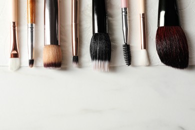 Photo of Set of different makeup brushes drying after cleaning on white table, flat lay. Space for text
