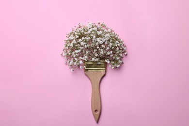 Creative composition with paint brush and gypsophila flowers on pink background, top view