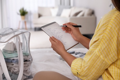 Photo of Pregnant woman writing packing list for maternity hospital at home, closeup