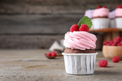 Sweet cupcake with fresh raspberries on wooden table. Space for text