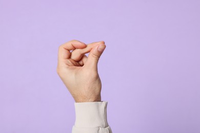 Man snapping fingers on violet background, closeup of hand. Space for text