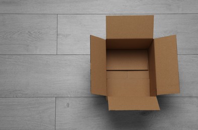 Empty open cardboard box on floor, top view. Space for text