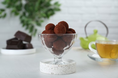 Photo of Dessert glass of delicious chocolate candies powdered with cocoa on white table