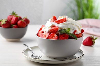 Delicious strawberries with whipped cream served on white wooden table