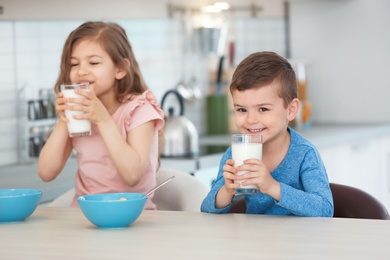 Cute little kids drinking milk in kitchen