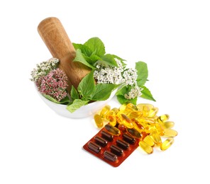 Mortar with fresh herbs and pills on white background