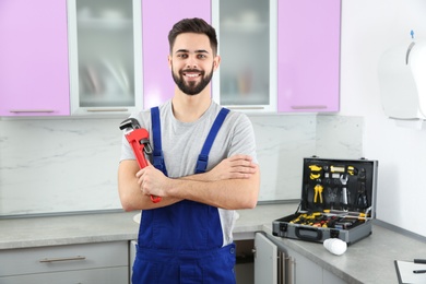 Male plumber with pipe wrench in kitchen. Repair service
