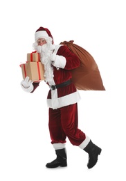 Photo of Santa Claus with sack and gifts walking on white background