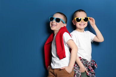 Portrait of cute twin brothers with sunglasses on color background. Space for text