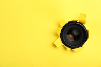 Hidden camera lens through hole in yellow paper. Space for text