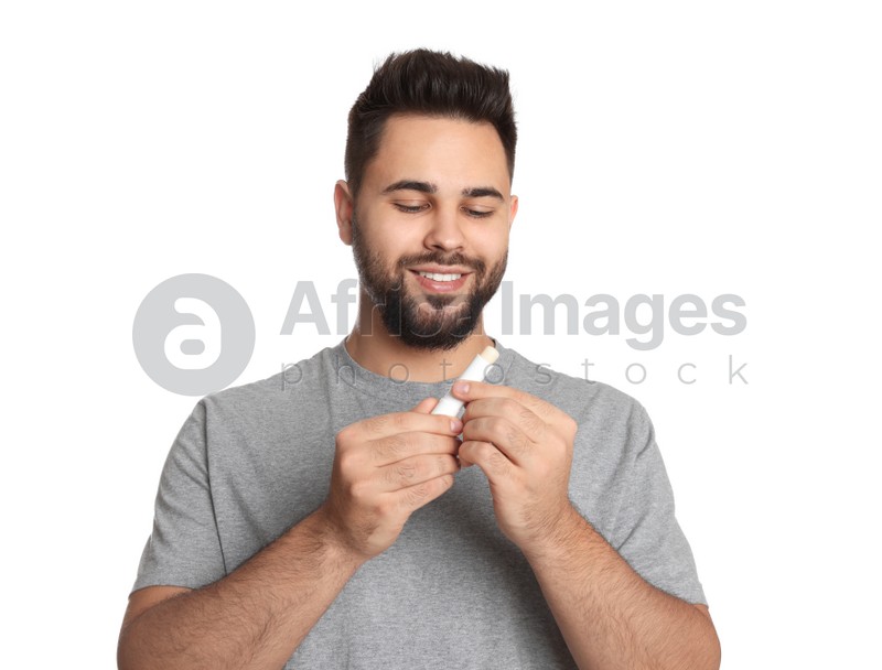 Young man with lip balm on white background