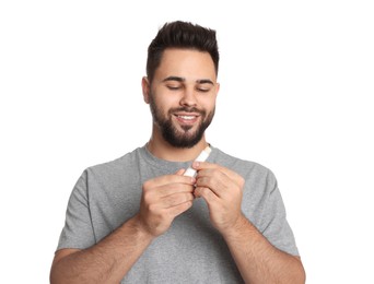 Young man with lip balm on white background