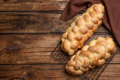 Homemade braided breads and cooling rack on wooden table, top view with space for text. Traditional Shabbat challah