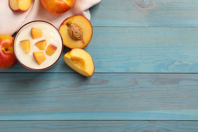 Tasty peach yogurt with pieces of fruit in glass on light blue wooden table. Space for text