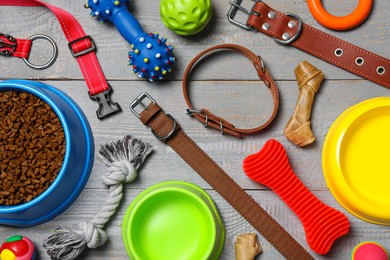 Photo of Flat lay composition with dog collars, toys and food on grey wooden table