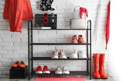 Shelving rack with stylish women's shoes and accessories near white brick wall indoors