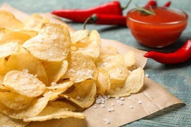 Delicious crispy potato chips with salt on table, closeup