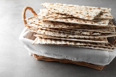 Traditional matzos in basket on light grey table, closeup