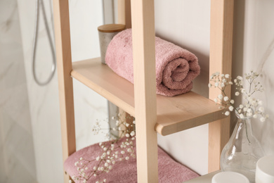 Photo of Shelving unit with clean towel in bathroom interior