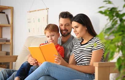 Happy family reading book together on sofa in living room at home