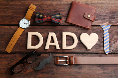 Photo of Flat lay composition with word DAD and heart on wooden background. Happy Father's day