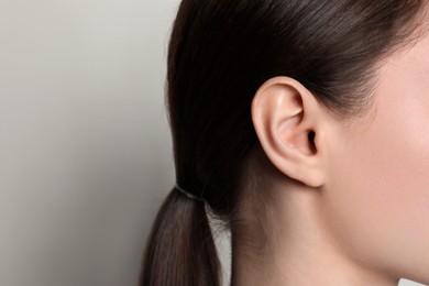 Woman on light background, closeup of ear. Space for text
