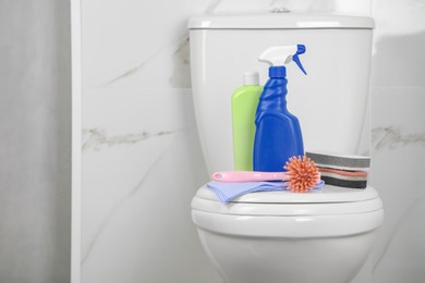 Photo of Cleaning supplies on toilet bowl in bathroom, space for text