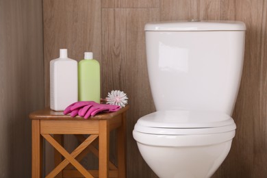 Photo of Cleaning supplies on stool near toilet bowl indoors
