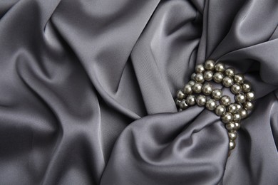 Beautiful pearls with grey silk as background, top view. Space for text