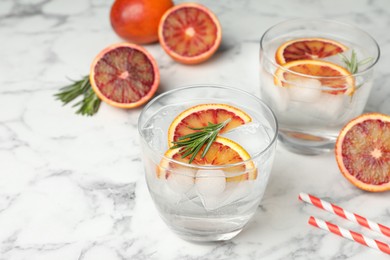 Delicious refreshing drink with sicilian orange and rosemary on white marble table