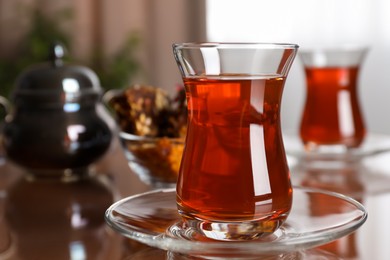 Photo of Glass with tasty Turkish tea on brown table indoors, closeup