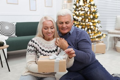 Happy mature couple with gift box at home. Christmas celebration