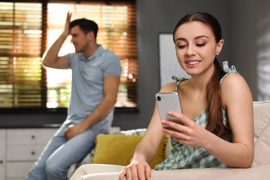 Woman preferring smartphone over spending time with her boyfriend at home. Jealousy in relationship